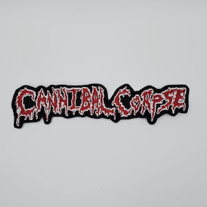 Op de afbeelding: Geborduurde patch met de tekst "CANNIBAL CORPSE" in rode, gestileerde letters met een zwarte rand. De patch heeft een rafelig, verweerd ontwerp, geschikt voor jassen of tassen.