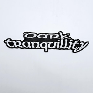 Könnte beinhalten: Ein schwarz-weißer, gestickter Aufnäher mit dem Schriftzug "Dark Tranquillity" in einer stilisierten Schriftart. Der Aufnäher hat einen schwarzen Hintergrund mit weißen Buchstaben und einem weißen Rand. Er ist für Kleidung gedacht.