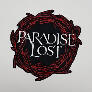 Peut inclure: Un écusson noir avec l'inscription blanche "PARADISE LOST", entourée d'une couronne d'épines rouge stylisée. Ce patch est destiné à être appliqué sur des vêtements ou des accessoires.