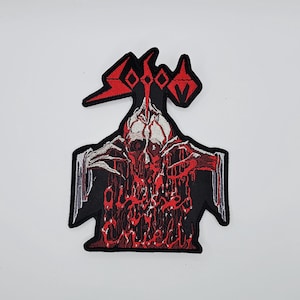 Könnte beinhalten: Gestickter Aufnäher mit einem roten und weißen Schädel mit tropfendem Blut und dem Text "Outlive the Chaos" in Rot. Der Aufnäher hat einen schwarzen Rand und ein rotes Logo oben. Das Design ist detailliert und hat ein gotisches Thema.