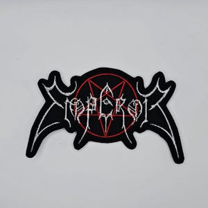 Puede incluir: Parche bordado negro con la palabra "EMPEROR" en letras góticas blancas. El parche presenta un pentagrama rojo dentro de un círculo negro, y formas blancas en forma de alas se extienden desde los lados.