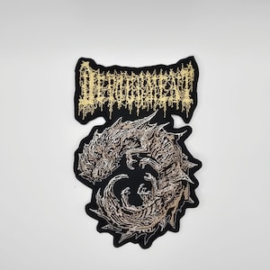 May include: A black patch featuring the word "DEROGEMENT" in gold thread above a detailed illustration of a dragon in shades of brown and tan. The dragon is coiled, with intricate scales and features.