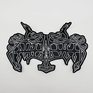 May include: Black and white embroidered patch with the word "ANOSUR" in a stylized font. The patch features two dragon-like figures at the top and a hammer symbol at the bottom. Intricate knotwork and decorative elements complete the design.