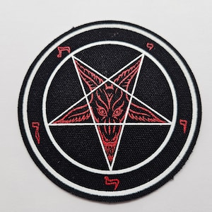 Peut inclure: Un écusson rond noir avec un bord blanc, représentant un pentagramme rouge avec un visage démoniaque au centre. Le design comprend des symboles sur le bord, pour la mode alternative ou les thèmes occultes.