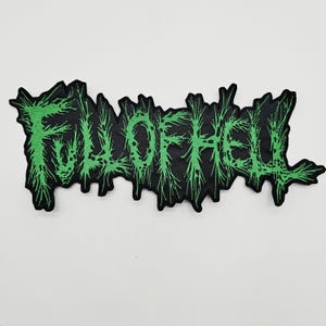May include: A black fabric patch featuring the text FULL OF HELL embroidered in a bright, neon green thread. The lettering is stylized with a jagged, thorny, and distressed aesthetic, creating a sharp, irregular outline against the black background.