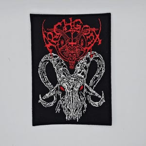 Op de afbeelding: Geborduurde zwarte patch met een witte geitenschedel met rode ogen en grote, gebogen hoorns. Boven de schedel bevindt zich een rood, gestileerd ontwerp. De patch is rechthoekig.