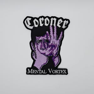 Pode incluir: Patch bordado com um gráfico estilizado em roxo e preto de um rosto e uma mão. A palavra "Coroner" está arqueada acima da imagem em branco, e "Mental Vortex" está abaixo. O patch é para roupas ou acessórios.