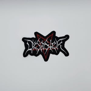 以下が含まれることがあります： 白の「Desaster」の文字が刺繍された黒いワッペン。赤い縁取りのある星型で、ジャケットやバッグ、その他の布製品に最適です。