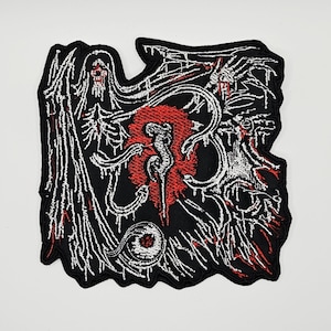 May include: A black embroidered patch featuring a white skeletal figure with wings, a central red circular element with a white abstract shape, and a detailed white eyeball at the bottom, all outlined in black thread against a black background.