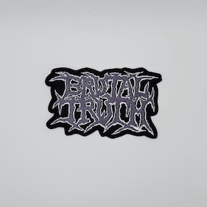 Puede incluir: Parche bordado en blanco y negro con el texto "BRUTAL TRUTH" en una fuente gótica estilizada. El parche tiene un borde irregular y un relleno de color púrpura claro.