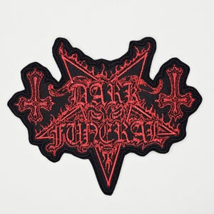 Può includere: Toppa ricamata nera e rossa con la scritta "DARK FUNERAL" all'interno di un pentagramma. Il design include croci decorative e dettagli a forma di fiamma, adatta per giacche o borse.