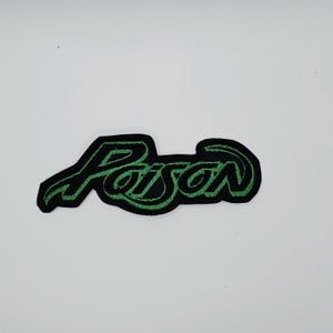Broderad lapp med giftgrön och svart logotypformad kant