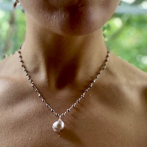 May include: A silver chain necklace with a large, off-white pearl pendant.
