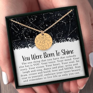 May include: A gold-colored necklace with a round pendant featuring a star map design. The pendant hangs on a delicate chain, presented in a black box with the text "You Were Born To Shine". The box has a starry background.