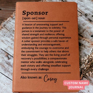May include: A brown leather journal with the word "Sponsor" defined as a beacon of support and guidance in the journey to sobriety. The journal also has the text "Also known as: Casey" and "CUSTOM NAME JOURNAL".