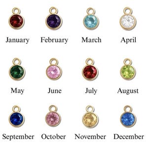 May include: A collection of twelve gold-colored pendants, each featuring a different colored gemstone. Each pendant is labeled with a month of the year, from January to December. The gemstones are various colors, including red, purple, blue, and green.