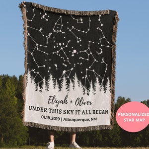 May include: A black woven throw blanket with a white constellation star map design and a white silhouette of a forest. The blanket has the text "Eliyah + Oliver UNDER THIS SKY IT ALL BEGAN 01.18.2019 | Albuquerque, NM" and "PERSONALIZED STAR MAP".