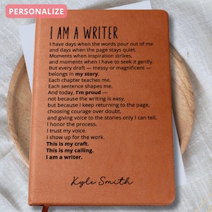May include: A brown leather journal with the text "I AM A WRITER" and a poem printed on the inside pages. The journal is personalized with the name "Kyle Smith" at the bottom. The word "PERSONALIZE" is in a pink box at the top.