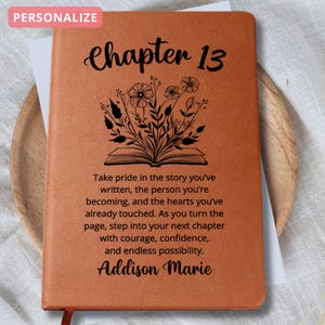 May include: An orange-brown journal with the text "Chapter 13" and a floral illustration. The journal features an inspirational quote and the name "Addison Marie". A red ribbon bookmark is visible. The word "PERSONALIZE" is in the top left corner.