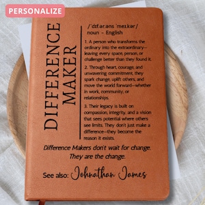 May include: A personalized orange leather-bound notebook with the words "DIFFERENCE MAKER" vertically printed on the left side. The notebook includes a definition and inspirational text. The text "See also: Johnathan James" is at the bottom.