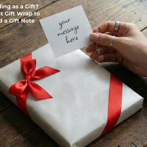 Pu&ograve; includere: Un regalo confezionato con un nastro e un fiocco rossi. Una piccola carta con le parole "your message here" &egrave; tenuta sopra il regalo. Il testo "Sending as a Gift? Select Gift Wrap to Add a Gift Note" &egrave; nell'angolo in alto a sinistra.