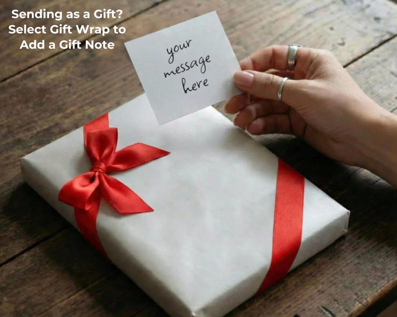 Pu&ograve; includere: Un regalo confezionato con un nastro e un fiocco rossi. Una piccola carta con le parole "your message here" &egrave; tenuta sopra il regalo. Il testo "Sending as a Gift? Select Gift Wrap to Add a Gift Note" &egrave; nell'angolo in alto a sinistra.