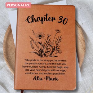 Może przedstawiać: Spersonalizowany, brązowy skórzany notatnik z napisem "Chapter 30" i kwiatowym wzorem. Notatnik zawiera inspirujący cytat i imię "Alex Marie".