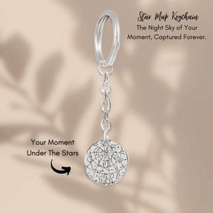 May include: A silver star map keychain with a circular pendant featuring a detailed star chart. The keychain includes the text "Star Map Keychain" and "The Night Sky of Your Moment, Captured Forever."
