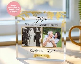 May include: A clear acrylic plaque commemorating a 50th wedding anniversary. It features two framed photos, gold floral accents, and the names "Jackie & Kent" with the date "10.24.1975". The text "50th WEDDING ANNIVERSARY" is displayed prominently.