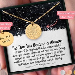 May include: A gold necklace with a star map pendant and a smaller round pendant that says "You are loved". The necklace is in a black box with a white background and the text "Personalized Star Map" and "Custom Back Engraving". The text "The Day You Became a Woman" is also on the box.