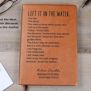 May include: A tan leather-like journal featuring the engraved text: LEFT IT IN THE WATER. The fear. The doubt. The need to know what comes next. I left it in the water. Today, I chose faith. I am forgiven. Alex Smith Baptized 03.13.2026 Southridge Church.