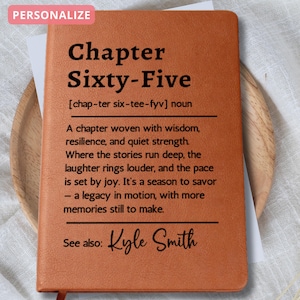 May include: A personalized, brown leather journal with the text "Chapter Sixty-Five" and a definition. The journal includes the name "Kyle Smith" and the word "PERSONALIZE" in a pink box.