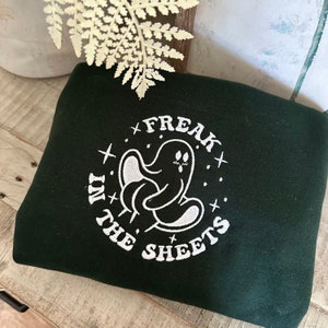 Może przedstawiać: Zielony sweter z białym haftem przedstawiającym ducha z napisem "Freak in the sheets".