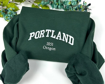 May include: A dark green sweatshirt with the text "PORTLAND 1851 Oregon" in white lettering.