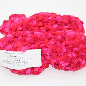 May include: Pink and red yarn balls with a label that reads "Bubbles" and "Lipstick". Dry cleaning is recommended. The yarn is 100% nylon and has a net weight of 2 oz and a yardage of 68 yds.