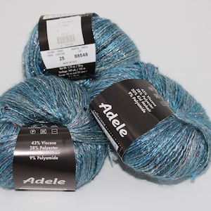 May include: Three balls of blue yarn with silver metallic thread and small red sequins. Each ball has a black label with the brand name "Adele" and fiber content information. The yarn is suitable for knitting and crochet projects.