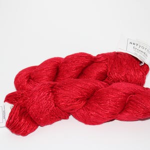May include: A skein of red yarn with two white labels that read "ARTyarns Ensemble".