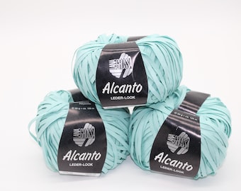 May include: Three balls of light blue yarn are stacked on a white background. Each ball has a black label with the text "Alcantro LEDER-LOOK" and "Lana Grossa" branding. Each ball weighs 50 g and is 125 m.