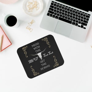 Puede incluir: Alfombrilla de ratón negra con un gráfico de cráneo de toro blanco y el texto "Mess with the Bull Get the Horns" en letras doradas.