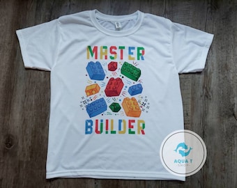 May include: White t-shirt with a colorful graphic of building blocks and the text "MASTER BUILDER".