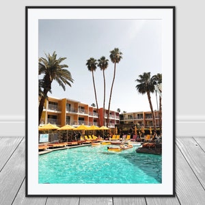 May include: A mid-century modern motel with a swimming pool surrounded by palm trees and yellow umbrellas. People are relaxing on lounge chairs and in the pool.