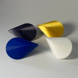 May include: Four cone-shaped objects in different colors: blue, white, gold, and dark purple. The cones are made of a smooth, textured material.