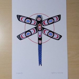 May include: A print featuring a stylized dragonfly design. The artwork showcases a black dragonfly with red, blue, and white accents, set against a white background. The dragonfly is centered within a red circle.