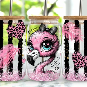 Puede incluir: Tres vasos de vidrio rayados en rosa y negro con tapas y pajitas. Cada vaso presenta un diseño diferente: un flamenco rosa con un lazo negro, un corazón rosa de estampado de leopardo y una hoja tropical rosa. Los vasos están llenos de purpurina rosa.