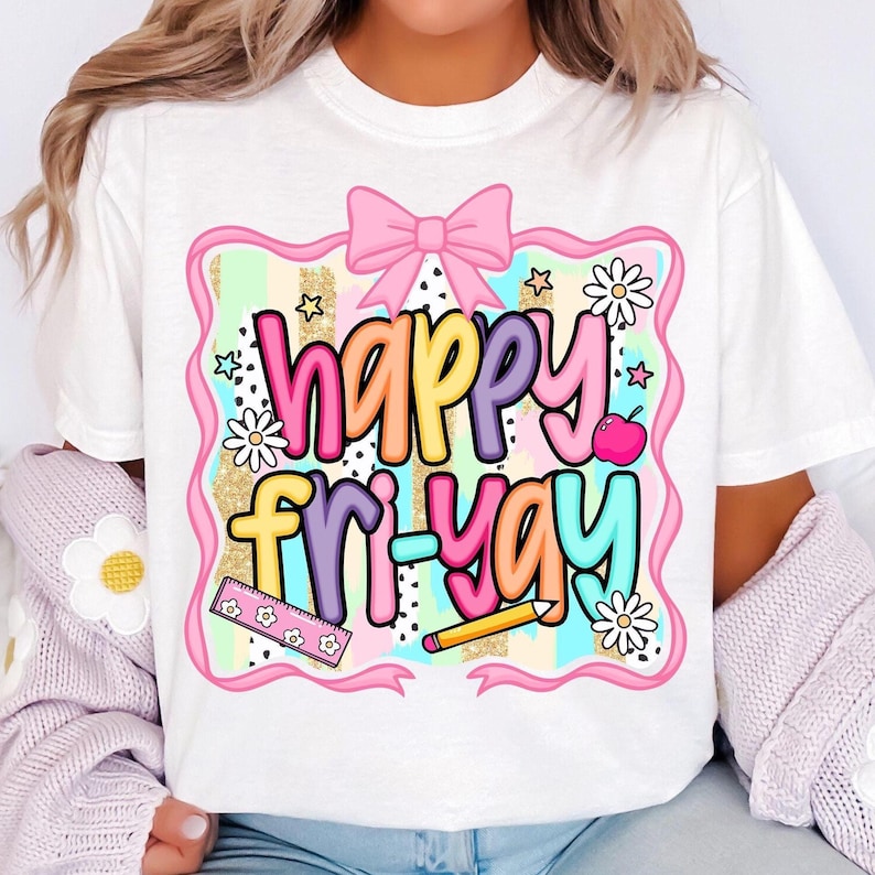 May include: White t-shirt with a colorful graphic that says "happy fri-yay." The design includes a pink bow, stars, daisies, an apple, a ruler, and a pencil. The text is in various colors, including pink, yellow, purple, and blue.