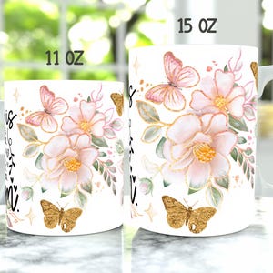 May include: Two white ceramic mugs with floral designs and gold accents. The mugs are 11 oz and 15 oz. The design features pink flowers, green leaves, and gold butterflies.