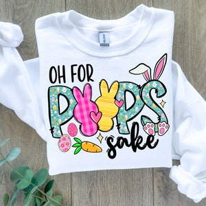 May include: White sweatshirt with a graphic design of Easter bunnies and the text "Oh for pups sake".
