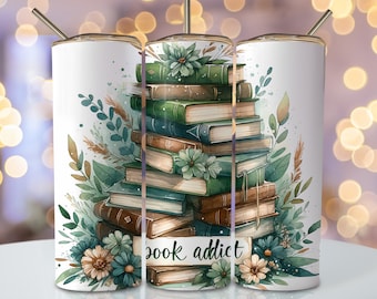 Peut inclure: Un gobelet blanc avec une pile de livres, des feuilles vertes et des fleurs. Le texte "book addict" est sur le devant du gobelet.