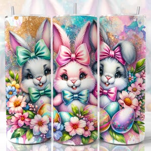 May include: Three stainless steel tumblers with a white background and colorful images of Easter bunnies with bows and flowers. The bunnies are wearing different colored bows, pink, blue, and green. The tumblers are decorated with pastel colors and glitter.