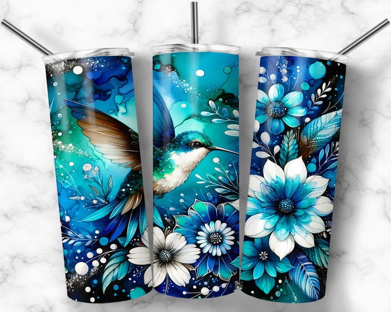 May include: Three stainless steel tumblers with different designs. The first tumbler features a blue and green hummingbird with white flowers. The second tumbler features a blue and green hummingbird with white flowers. The third tumbler features blue and white flowers.